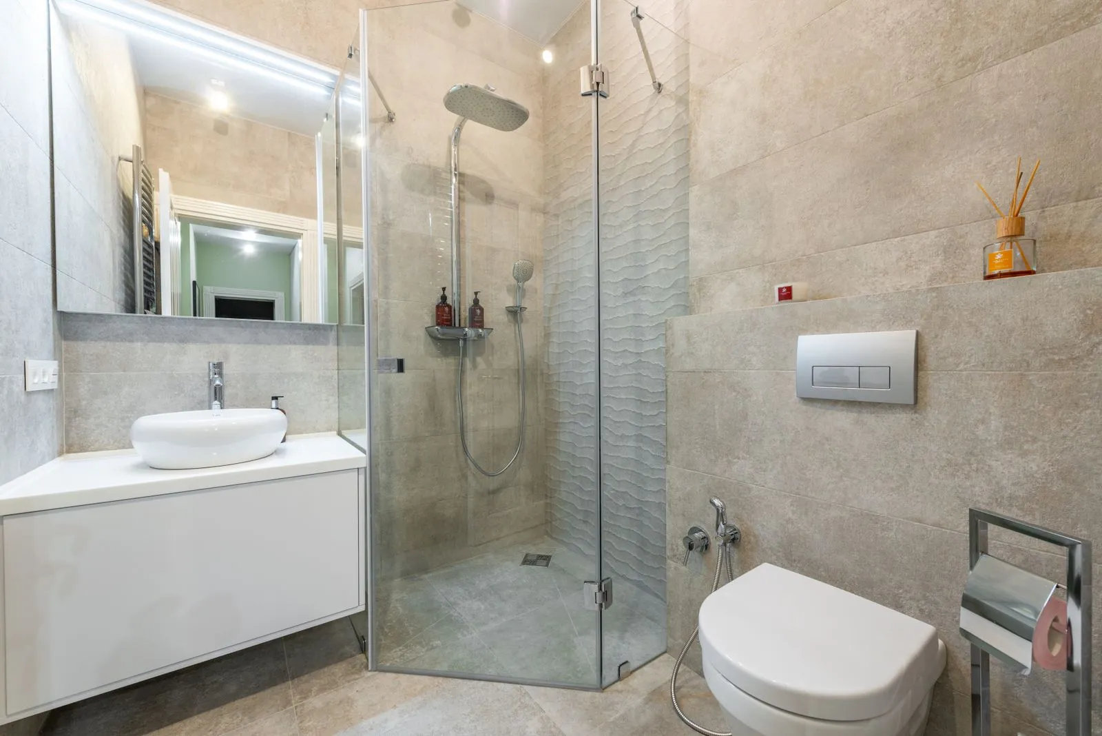 Contemporary shower room between cabinet with washstand and toilet bowl on tiled floor at home